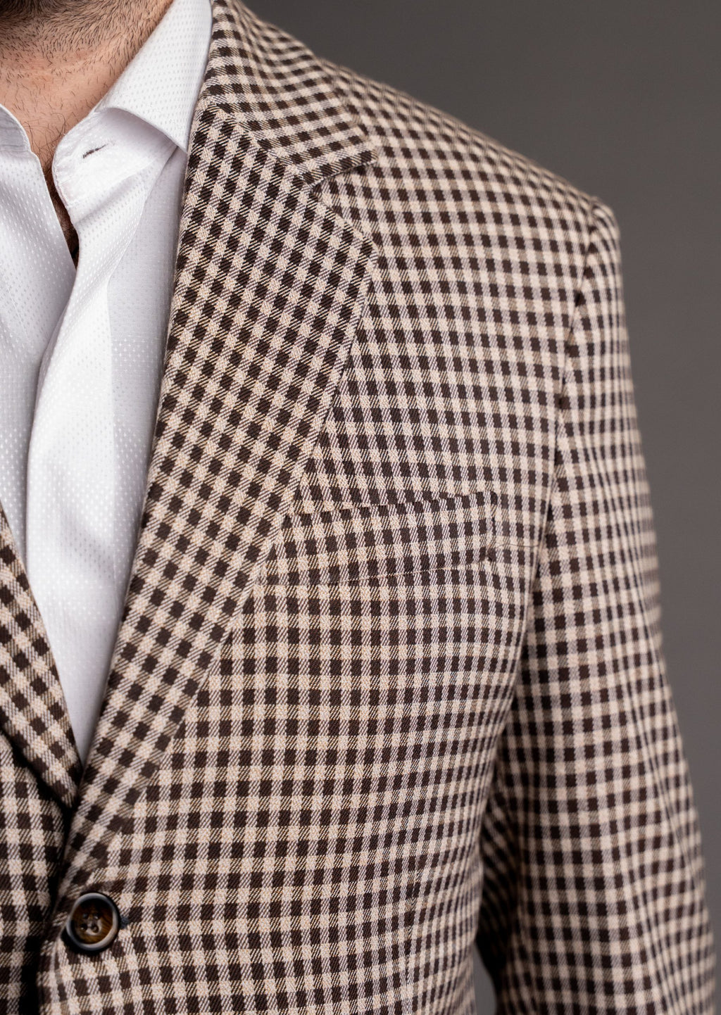 Beige and brown plaid men's blazer with a tailored fit, featuring classic lapels and pocket details.