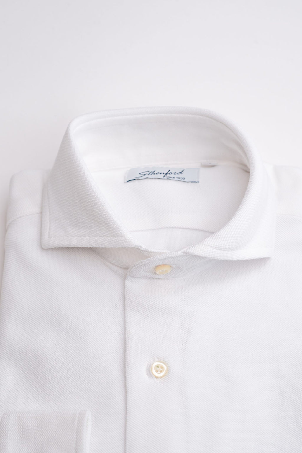 White men's shirt by Sthenford, style CMS02AS, displayed on a hanger with a close-up of fabric and collar details.