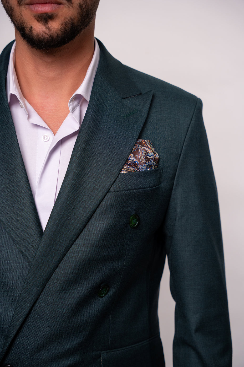 Close-up of a men's costume jacket with two rows of dark green buttons, showcasing the detailed fabric and tailored fit.