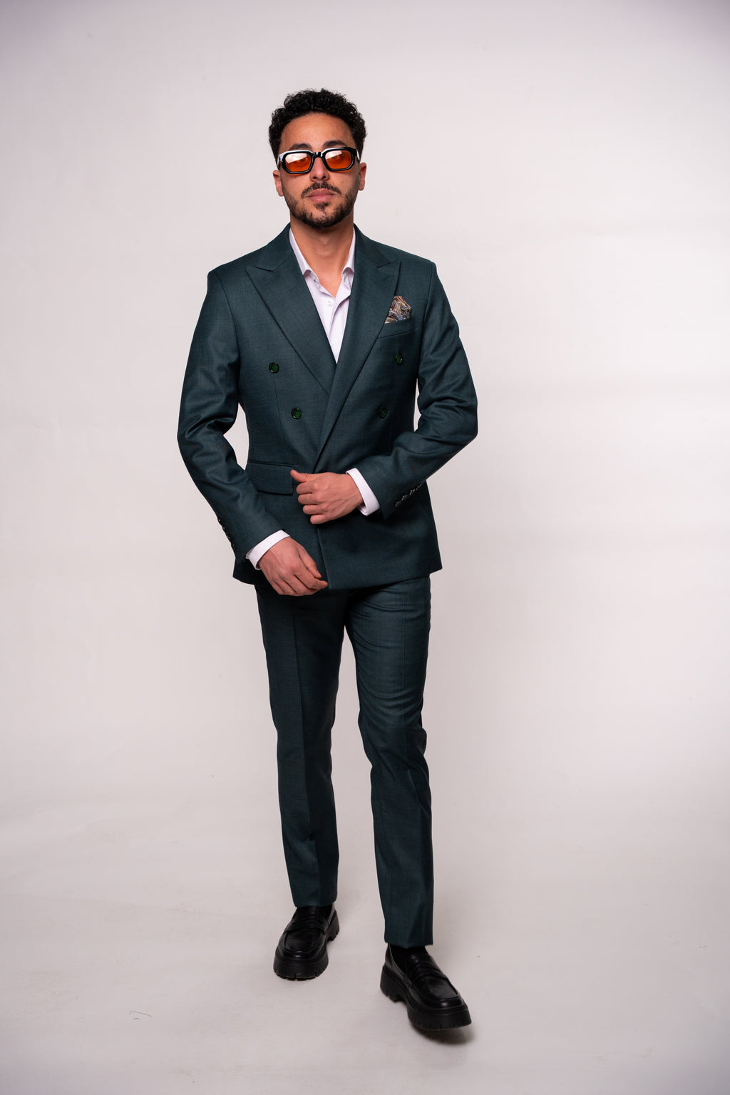 Close-up of men's dark green double-breasted blazer with two rows of buttons, showcasing tailored style and fabric details.