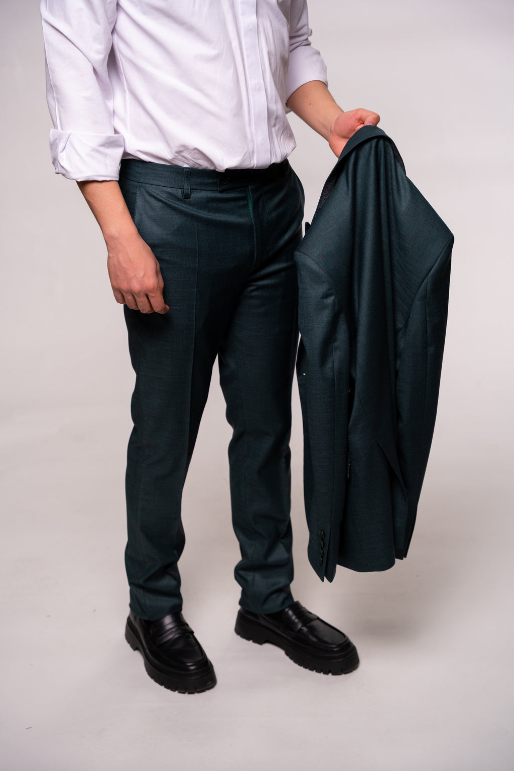 Dark green men's costume jacket from Couture for Gentlemen, shown on a hanger with detailed fabric texture.