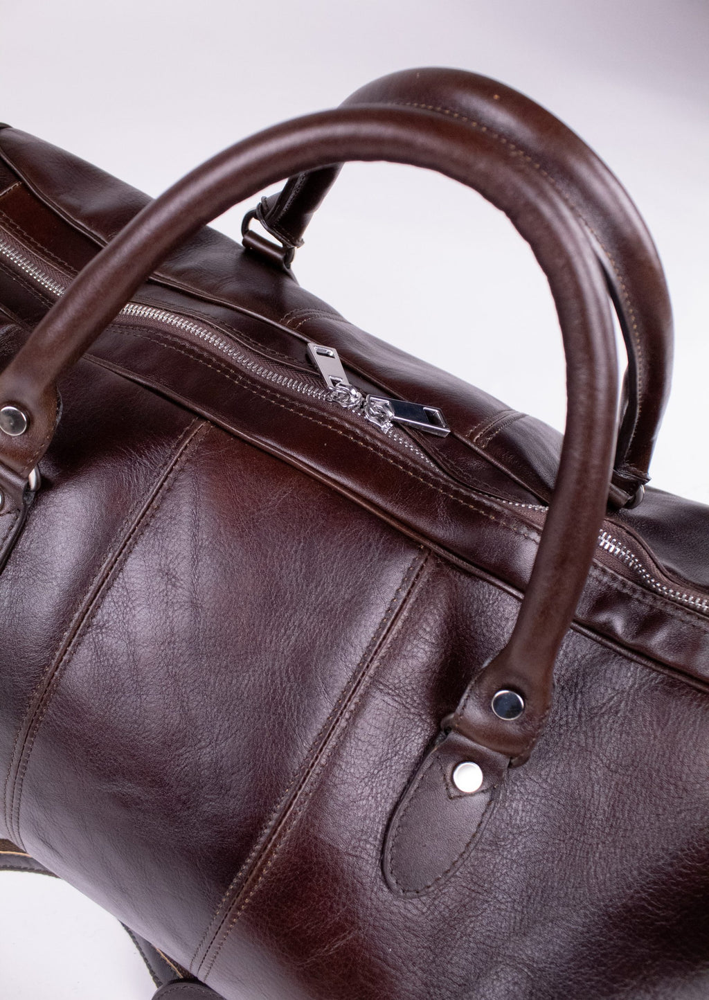 Natural brown leather travel bag with sturdy handles and zipper closure, showcasing a stylish and durable design.