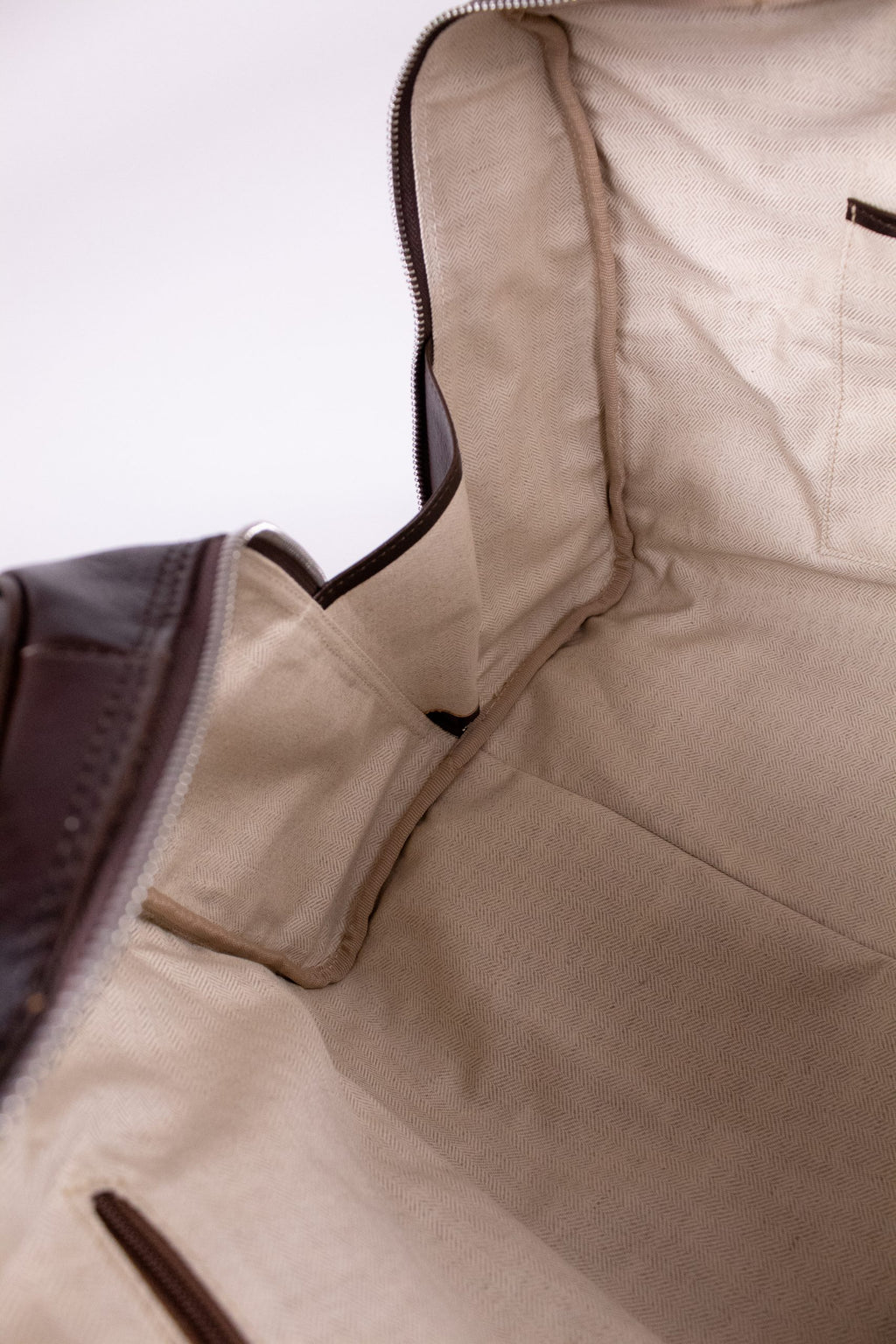 Natural brown leather travel bag with sturdy handles and zipper closure, perfect for stylish journeys.