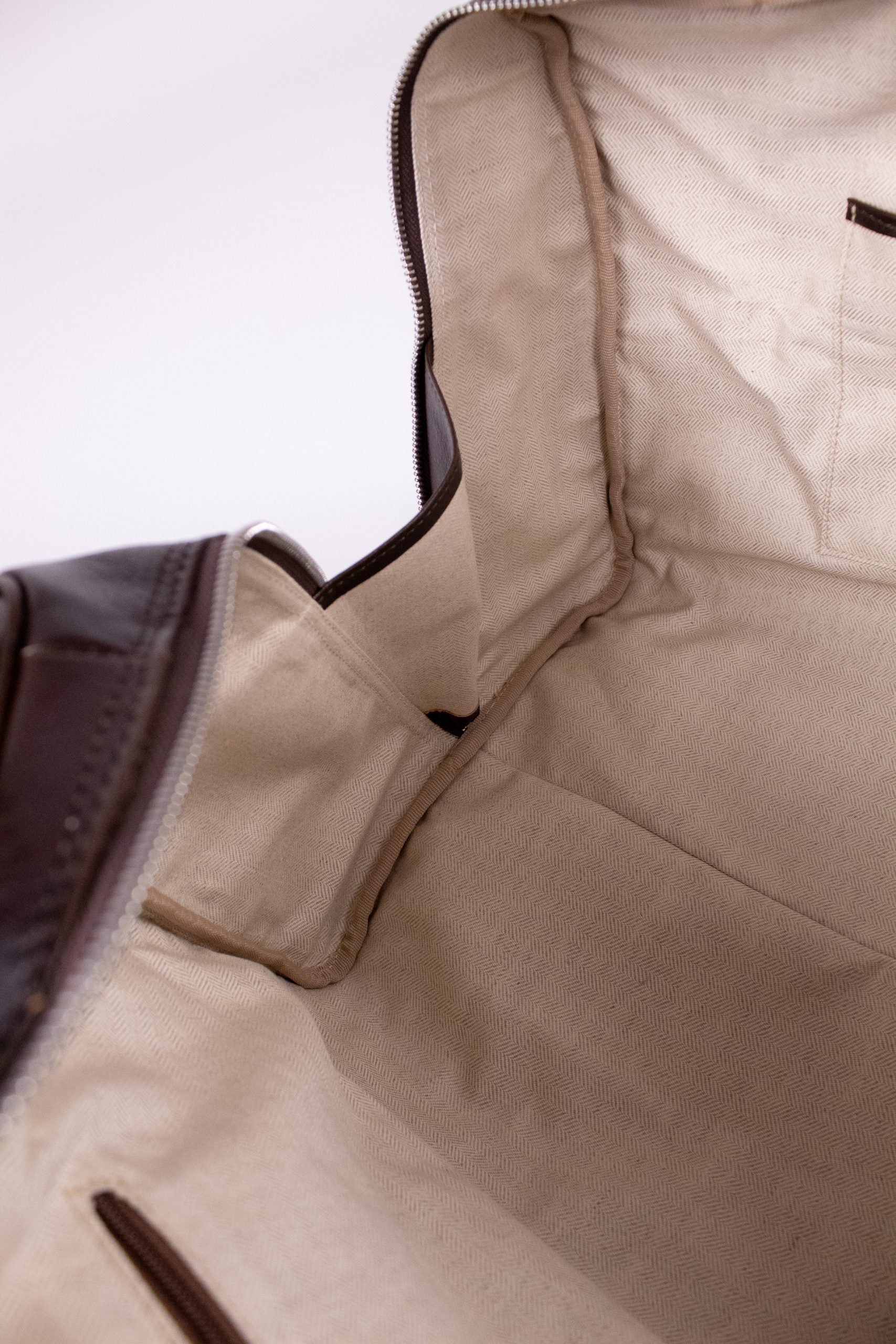 Natural brown leather travel bag with sturdy handles and zipper closure, perfect for stylish journeys.