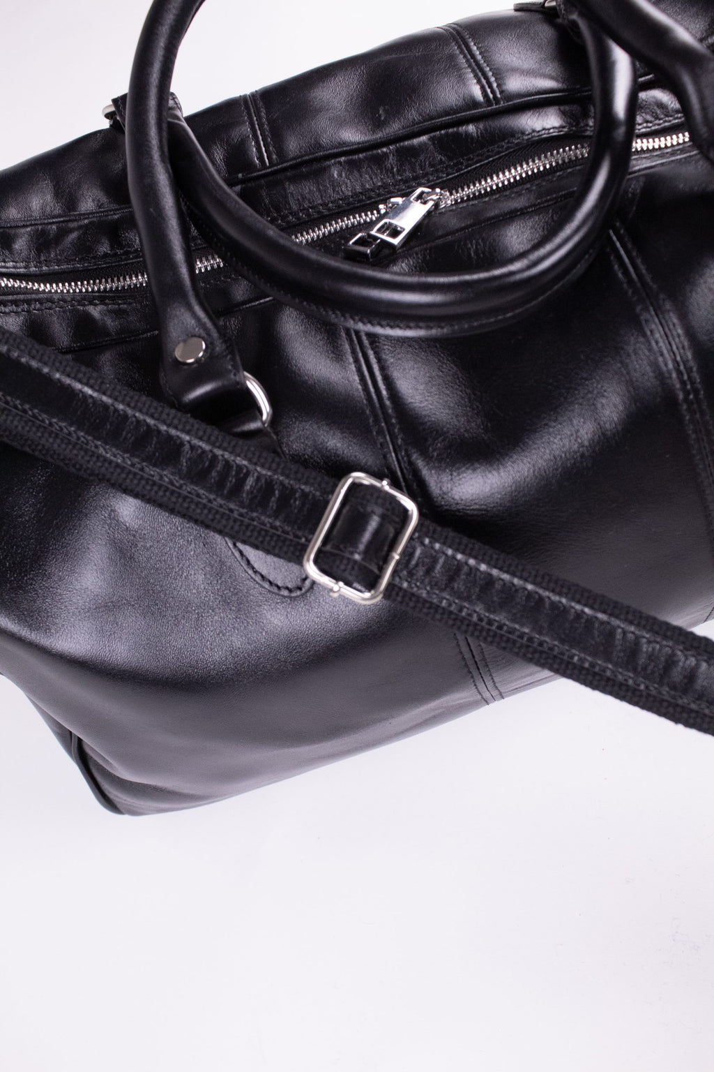 Black genuine leather travel bag with sturdy handles and sleek design, perfect for stylish trips and carry-on convenience.