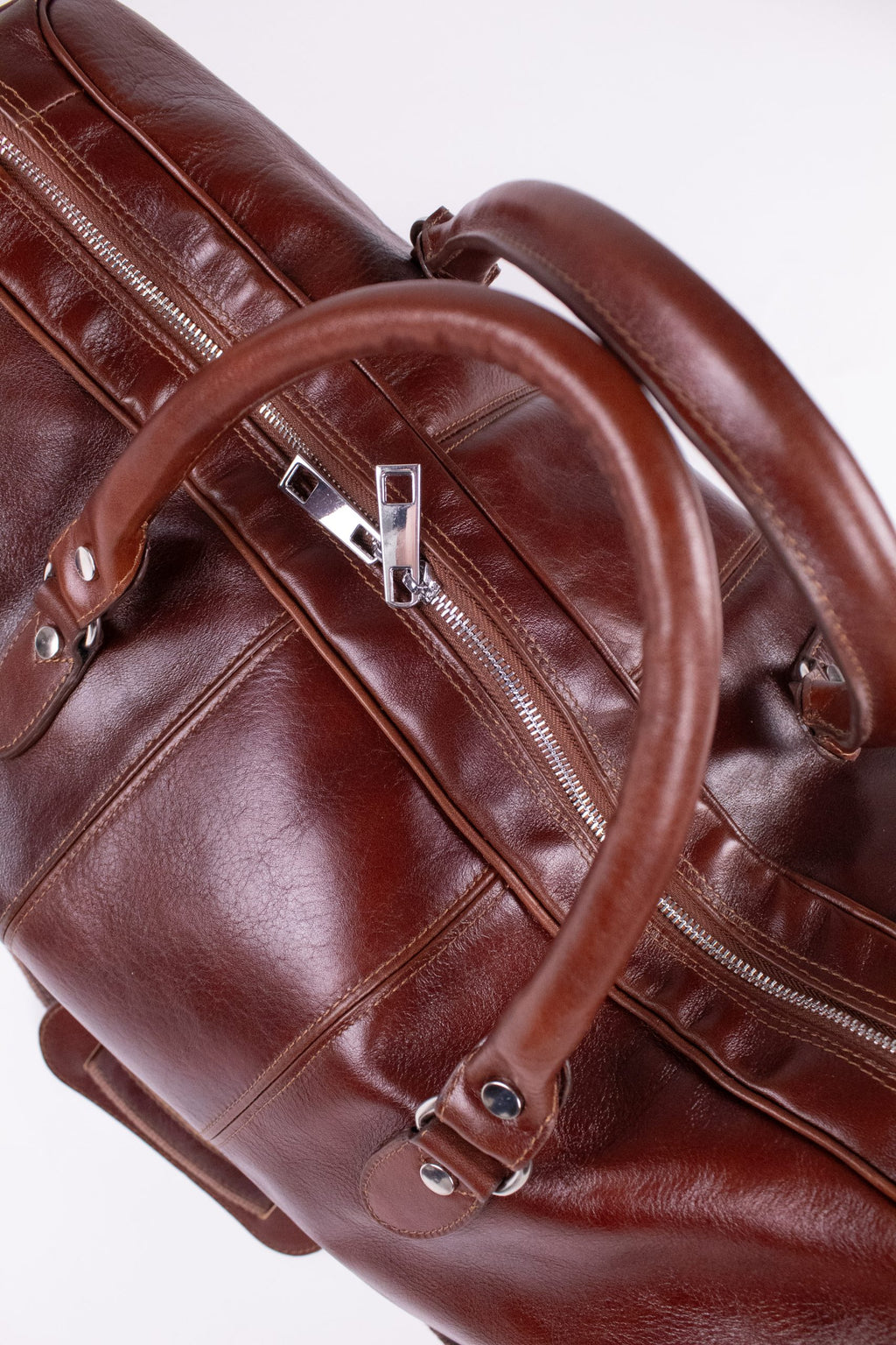 Natural brown leather travel bag with sturdy handles and spacious interior, designed for stylish and practical journeys.