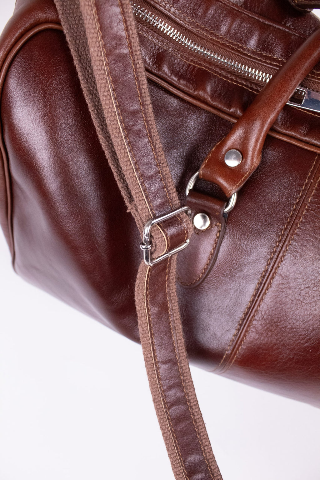 Brown natural leather travel bag with sturdy handles and brass hardware, designed for stylish, durable luggage.