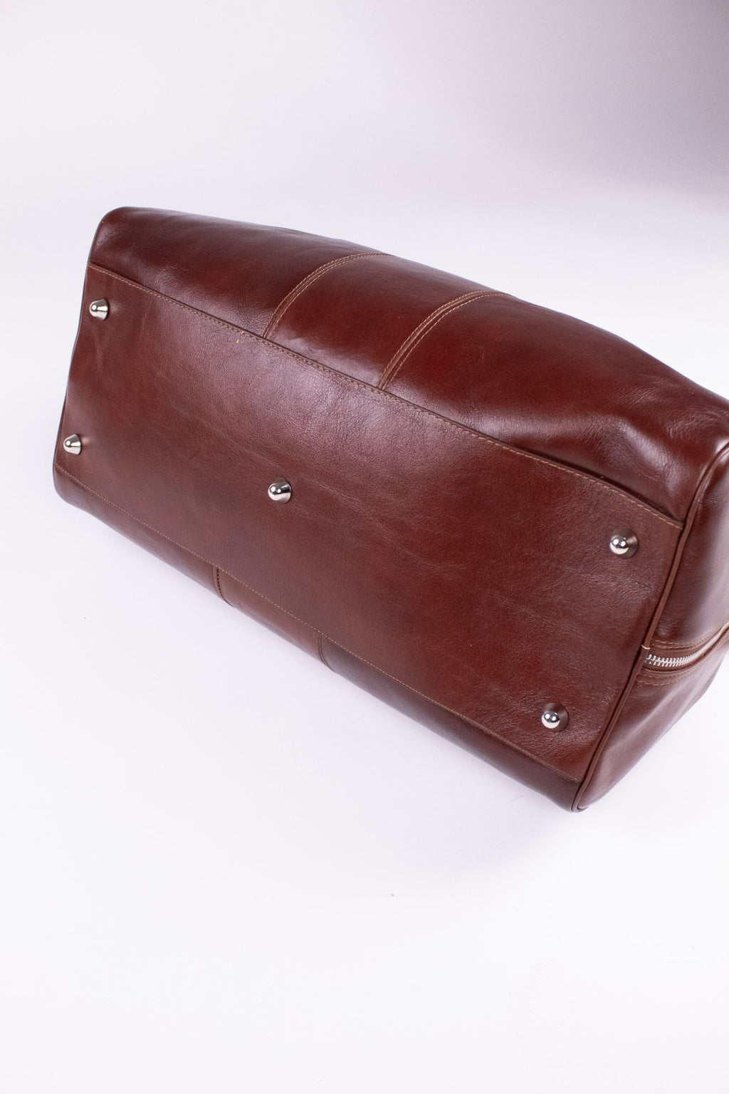 Brown genuine leather travel bag with sturdy handles and brass hardware, designed for stylish, durable travel accessories.
